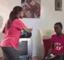 a woman in a pink shirt is dancing in front of a television while another woman watches .
