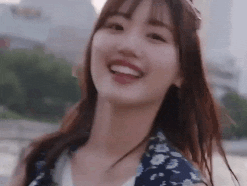 a young woman is smiling and looking at the camera while standing in front of a body of water .