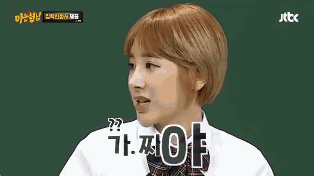 a woman with short blonde hair is talking in front of a chalkboard while wearing a school uniform ..