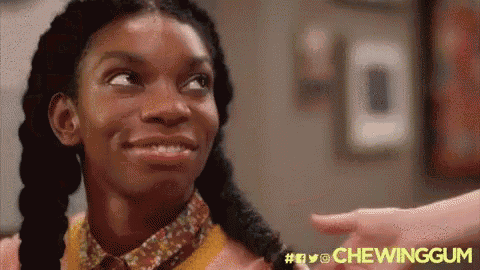 a woman with pigtails is smiling and pointing at someone while chewing gum .