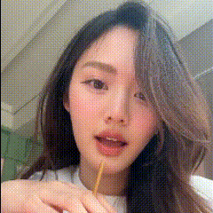 a woman with long hair is holding a stick in her mouth .