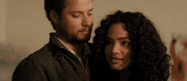 a man with a beard and a woman with curly hair are looking at each other