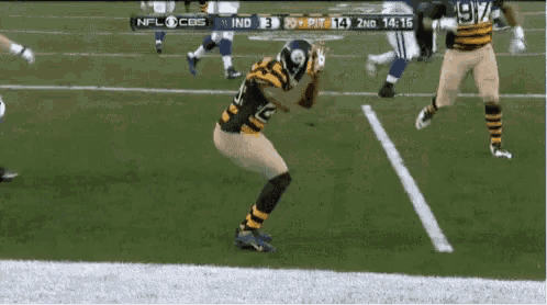 a football player in a black and yellow uniform is kneeling on the field during a game .