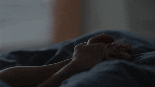 a close up of a person laying in bed with their hands on their feet