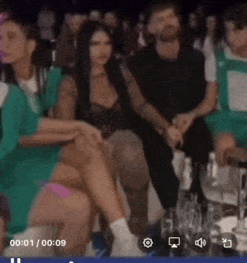 a group of people are sitting in a room with a woman sitting on a man 's lap .