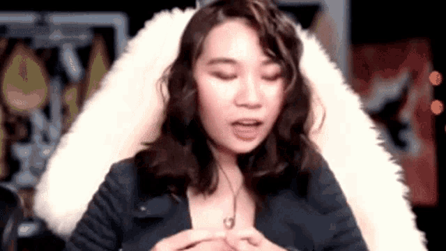 a woman is sitting in a chair with her eyes closed and a furry blanket .