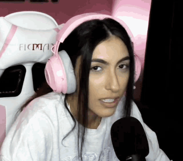 a woman wearing pink headphones and a white shirt is sitting in a pink chair .