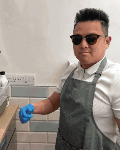 a man wearing sunglasses and an apron holds a blue glove in his hand