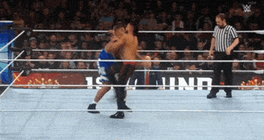 two men are wrestling in a ring with a referee and a sign that says 1st inning