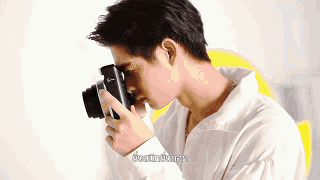 a man in a white shirt is taking a picture with a camera with a t on it