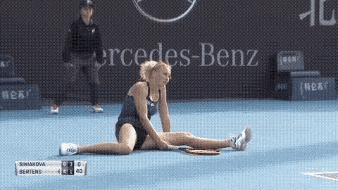 a woman is sitting on a tennis court with a mercedes benz ad in the background