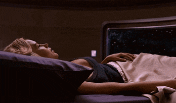 a woman in a black top is laying on a bed with her eyes closed