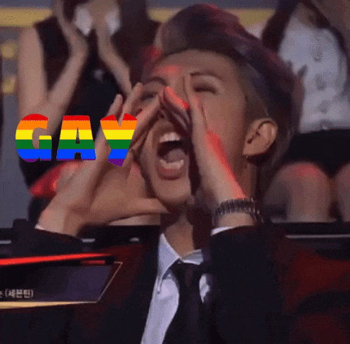 a man in a suit and tie is shouting with the word gay in rainbow letters