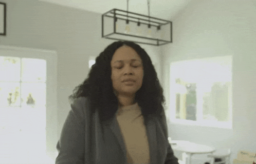a woman is standing in a living room with her eyes closed and looking at the camera .