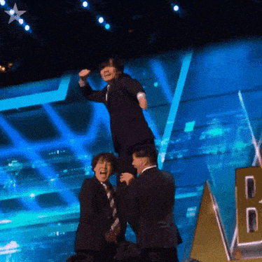 a man in a suit is being lifted by two other men on stage