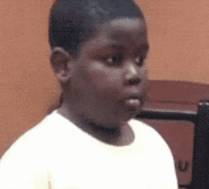 a young boy in a white shirt is looking at the camera .
