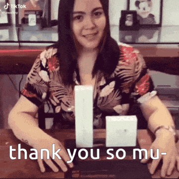 a woman sitting at a table with two boxes and the words thank you so mu