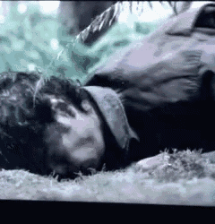 a man is laying on the ground in the grass with his eyes closed .