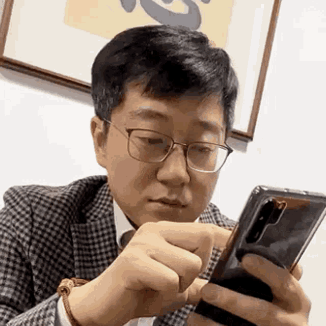 a man wearing glasses is using a cell phone .