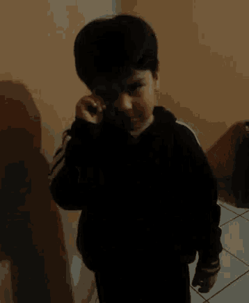 a young boy in a black and white striped shirt is pointing at something