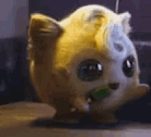 a stuffed animal with a green object in its mouth is sitting on a table .