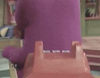a purple and green cartoon character talking on a telephone
