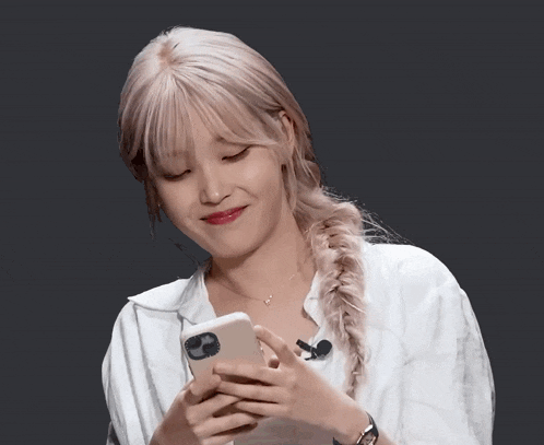 a woman wearing a braided ponytail is looking at her phone