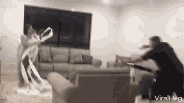 a man and a woman are fighting in a living room with a couch in the background .