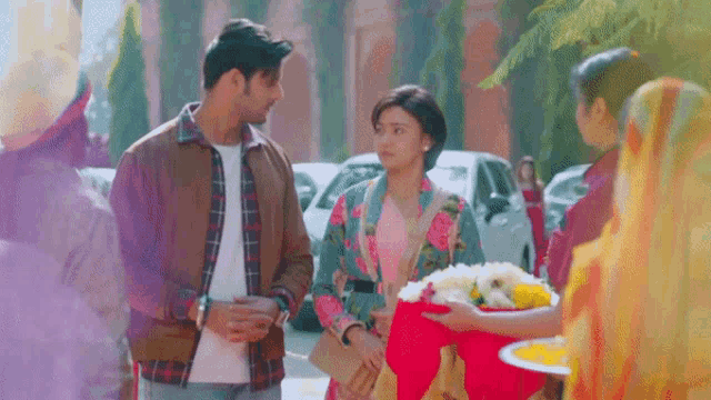 a man and a woman are standing next to each other and a woman is holding a bouquet of flowers