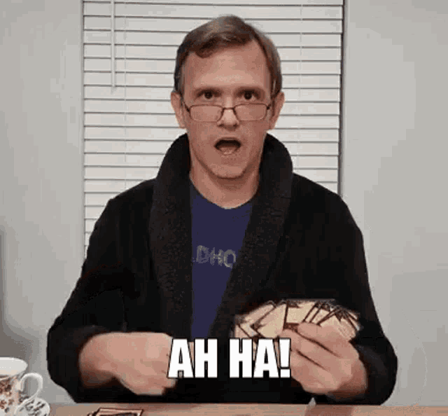 a man in a robe and glasses is holding a stack of cards and making a face .