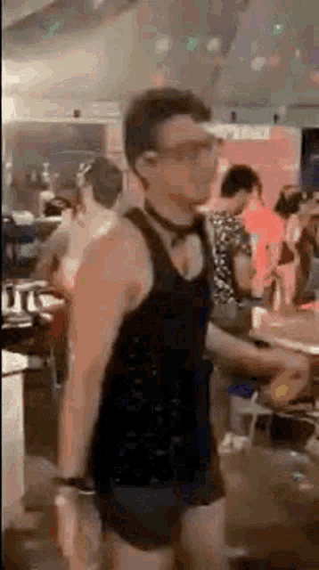 a man in a black tank top and shorts is standing in front of a crowd of people .