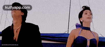 a man and a woman are standing next to each other on a boat and looking up at the sky .