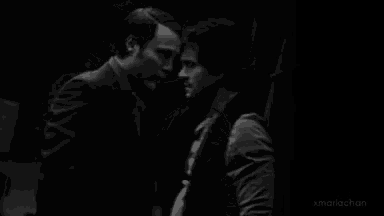 a black and white photo of two men standing next to each other and looking at each other .