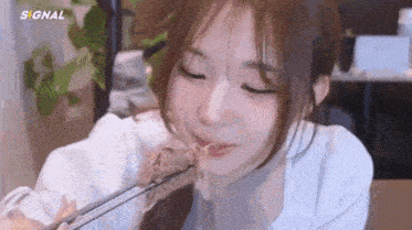 a young woman is eating food with chopsticks and smiling .