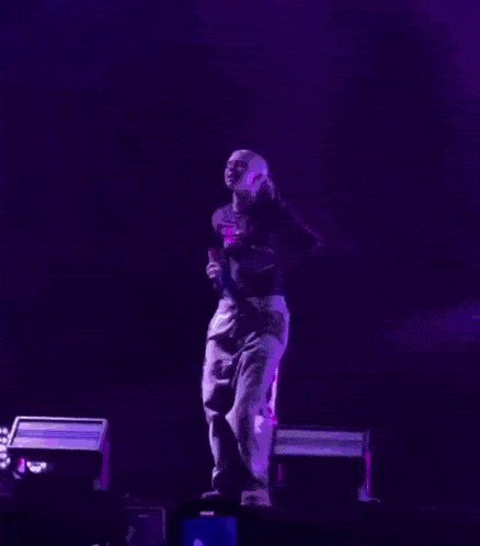 a man is singing into a microphone on a stage with purple lights