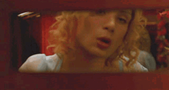 a woman in a blue dress is looking through a window with her mouth open