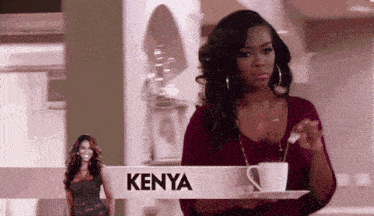 a woman is holding a cup of coffee in front of a kenya sign