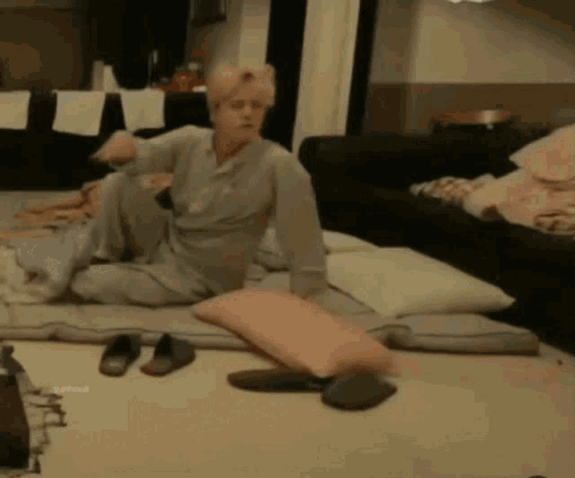 a man is sitting on the floor in a living room with pillows and a couch .