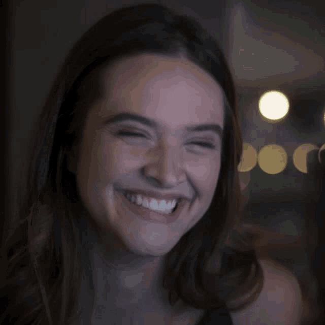 a close up of a woman 's face smiling with a blurry background