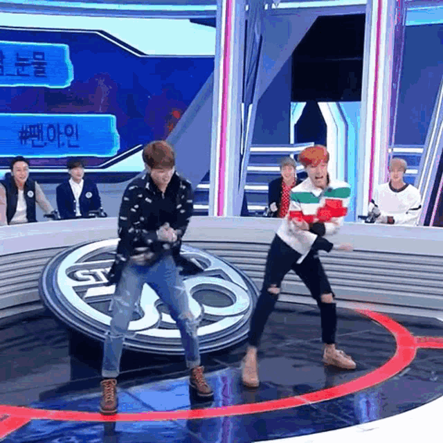 a group of young men are dancing on a stage in front of a sign that says ' sbs ' on it