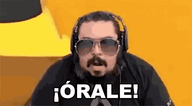 a man with a beard and sunglasses is wearing headphones and a black shirt .