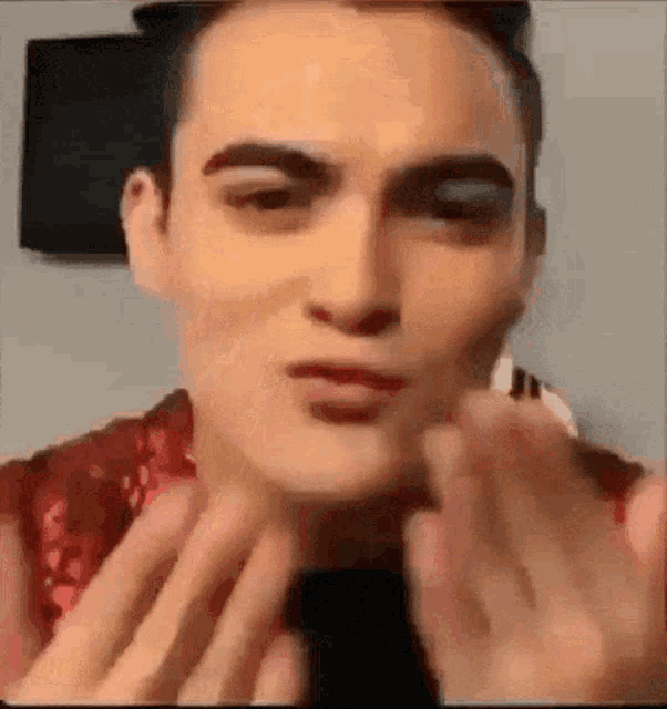 a close up of a man 's face with his hands on his face .
