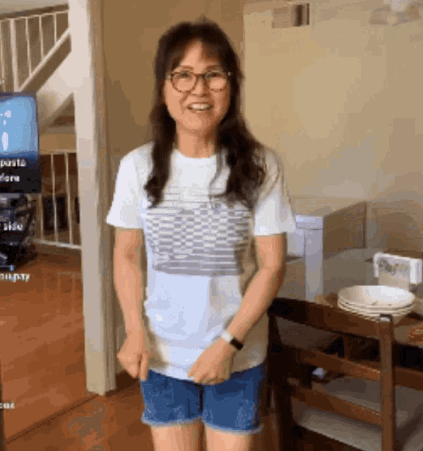 a woman wearing shorts and a white shirt is standing in front of a tv that says pasta