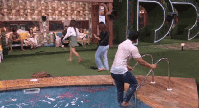 a group of people are standing around a swimming pool with a sign that says dd on it