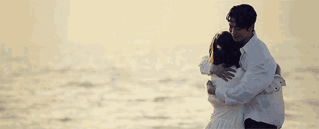 a man is carrying a woman in his arms on a beach .