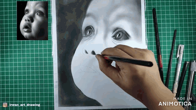 a person is drawing a baby 's face on a piece of paper
