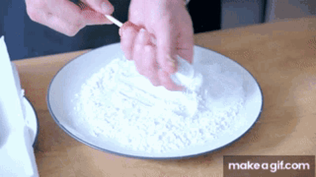 a person is dipping a stick in powdered sugar on a plate