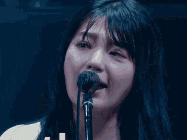 a woman singing into a microphone with tears coming out of her eyes