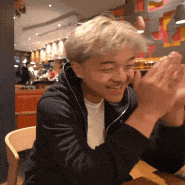a man in a black jacket is clapping his hands