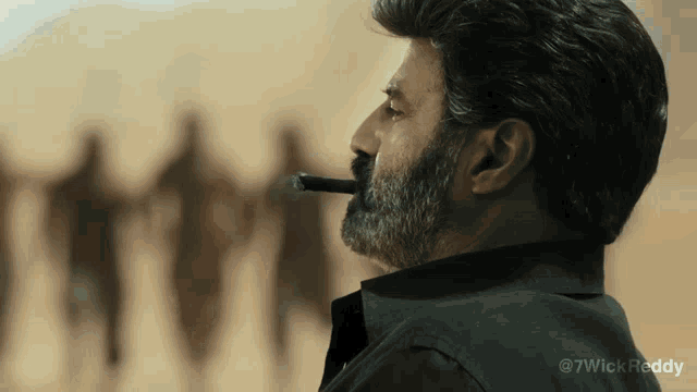 a man with a beard is smoking a cigar in front of a desert scene